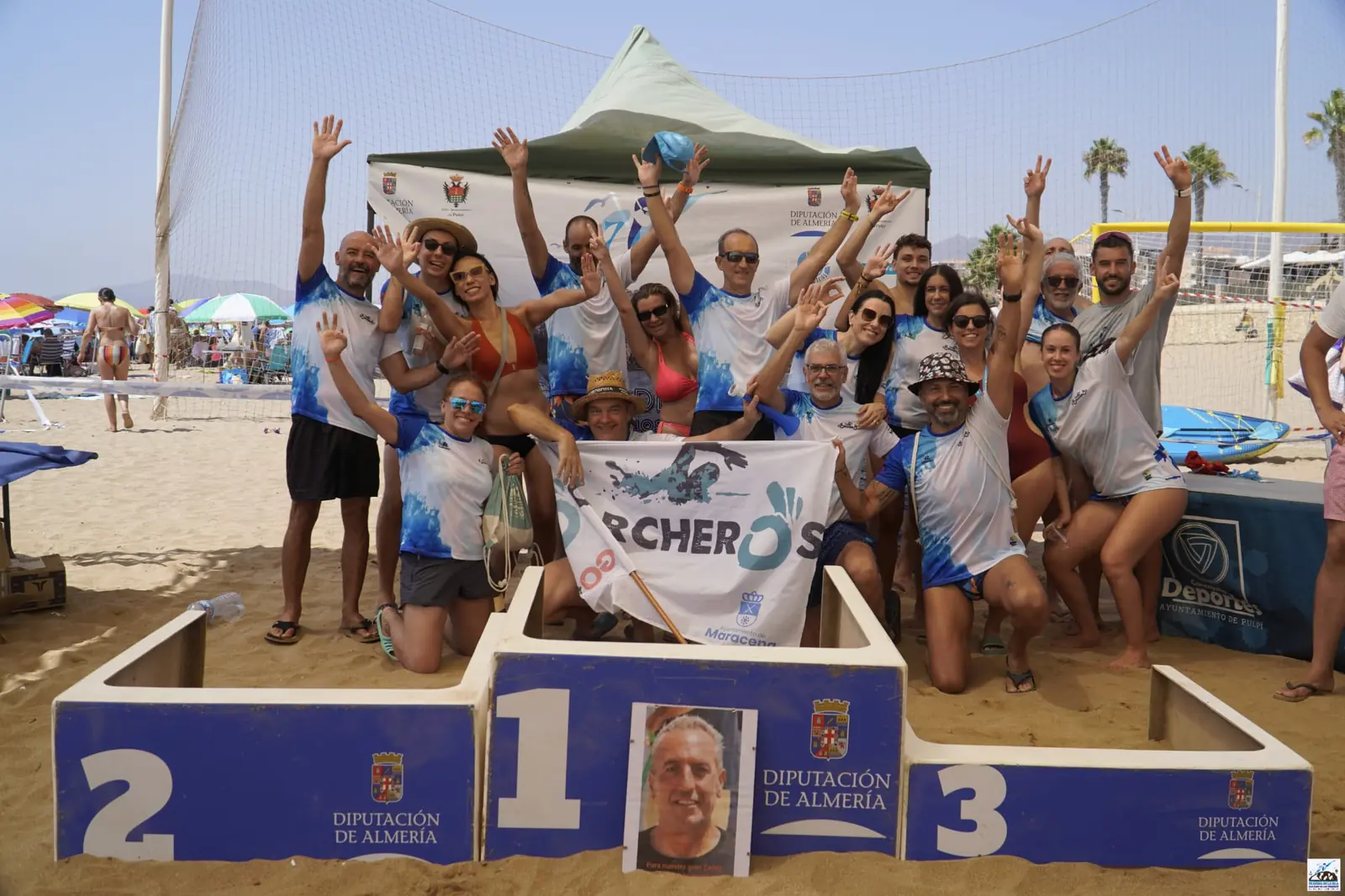 El CN Corcheros celebrando en el podio con su pancarta después de la travesía
