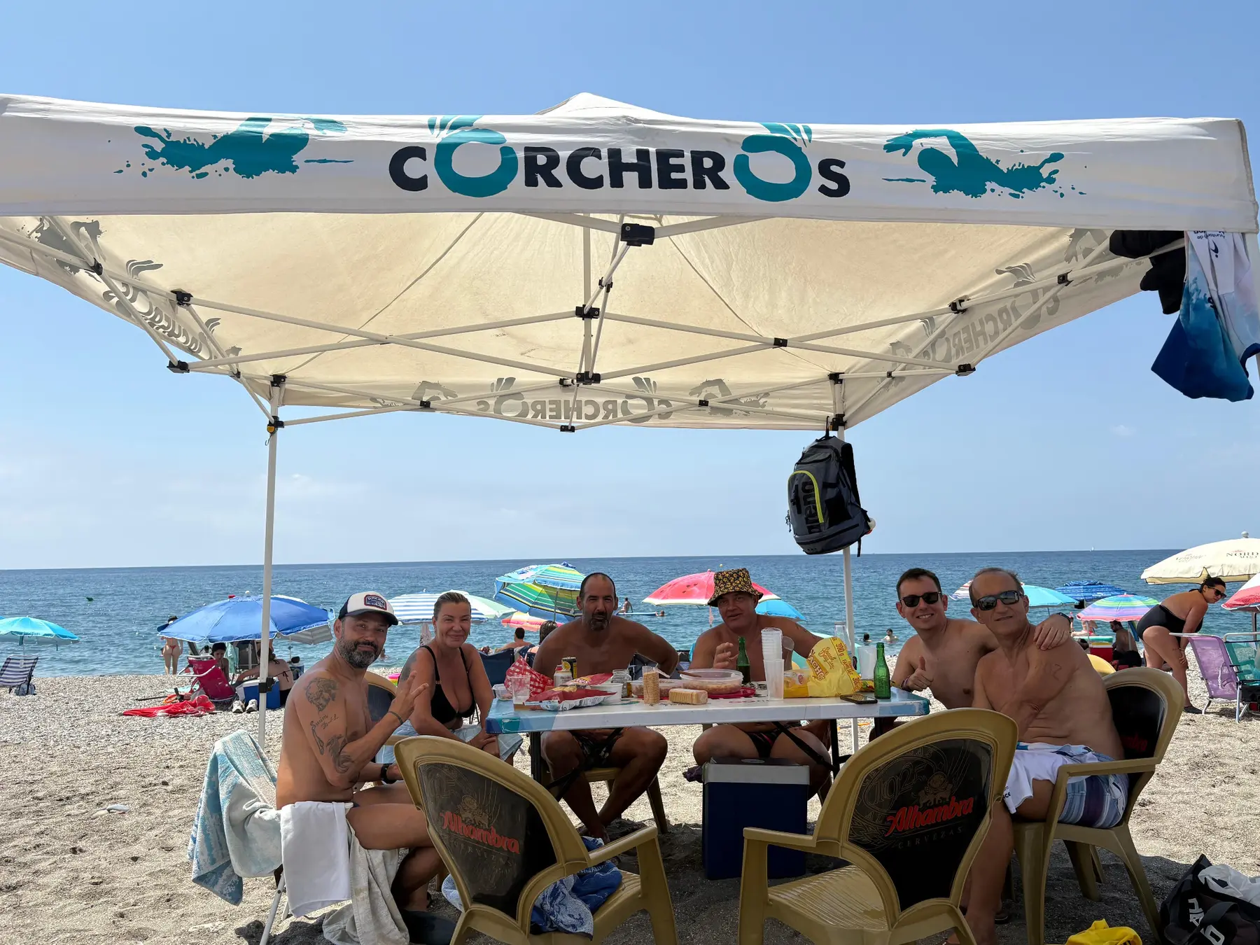 Un grupo de Corcheros compartiendo pícnic y charla bajo la carpa del club en la playa de Torrenueva